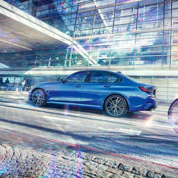 Седан BMW 3 серии, вид сбоку G20 Стоп-кадр седана BMW 3 серии сбоку в дневное время на фоне здания со стеклянным фасадом G20.