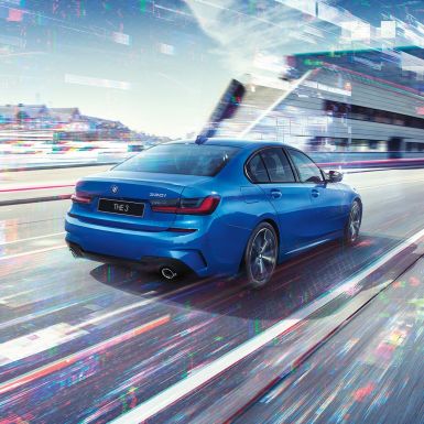 Седан BMW 3 серии, вид сзади сбоку G20 Седан BMW 3 серии, вид сзади с поворотом в три четверти, в дневное время на фоне города G20.