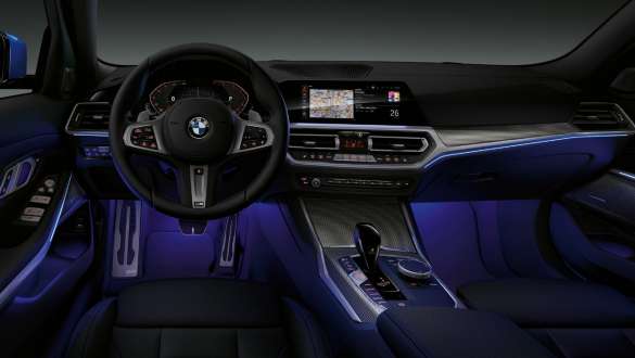 Седан BMW 3 серии, подсветка Ambient light G20 Вид спереди места водителя седана BMW 3 серии с подсветкой Ambient light синего цвета пространства для ног G20.