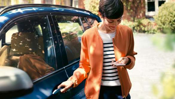 Женщина смотрит в смартфон Женщина выходит из BMW, глядя в смартфон