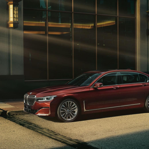 BMW 7 серии Individual: вид сбоку BMW 7 серии Individual красного цвета: вид сбоку на фоне городского пейзажа