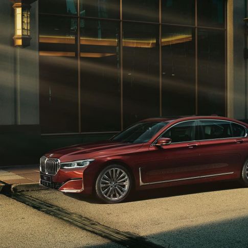 BMW 7 серии Individual: вид сбоку BMW 7 серии Individual красного цвета: вид сбоку на фоне городского пейзажа