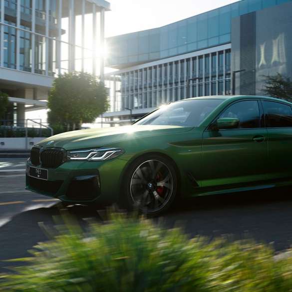 BMW M550i xDrive G30 LCI Facelift 2020, вид сбоку в движении BMW M550i xDrive G30 LCI Facelift 2020, BMW Individual "Зеленый Эрмес металлик", на городской улице, вид сбоку
