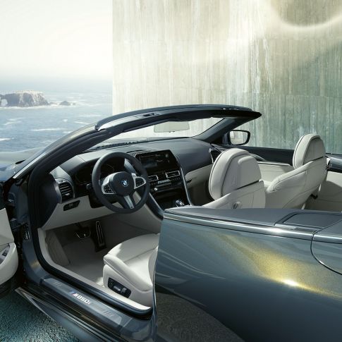 BMW M850i xDrive Cabrio, интерьер. BMW M850i xDrive Cabrioс открытым мягким верхом, Серый Дравит металлик, интерьер с акцентом на обтянутое кожей рулевое колесо M и отделку кожей Merino BMW Individual цвета «Слоновая Кость».
