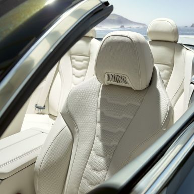 BMW M850i xDrive Cabrio, многофункциональные сиденья водителя и пассажира. BMW M850i xDrive Cabrio с открытым мягким верхом, Серый Дравит металлик, интерьер с акцентом на многофункциональные сиденья с отделкой кожей Merino BMW Individual цвета «Слоновая Кость».