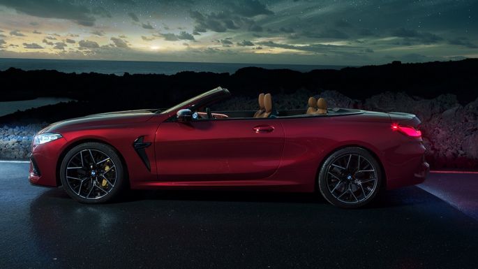BMW M8 Competition Cabrio, вид сбоку. BMW M8 Competition Cabrio с открытым мягким верхом, Красный Мотеги металлик, вид сбоку, неподвижный автомобиль под звездным небом.