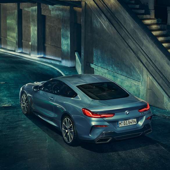BMW M850i xDrive Coupe, вид сзади слева с поворотом в три четверти G15. BMW M850i xDriveCoupe, Синий Барселона металлик, вид сзади слева с поворотом в три четверти, неподвижный автомобиль в темное время суток G15.