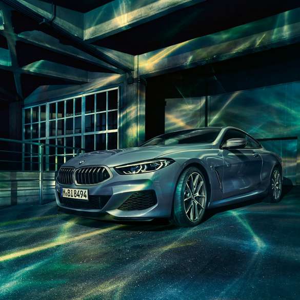 BMW M850i xDrive Coupe, вид спереди с поворотом в три четверти. BMW M850i xDriveCoupe, Синий Барселона металлик, вид спереди с поворотом в три четверти, неподвижный автомобиль перед зданием.