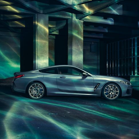 BMW M850i xDriveCoupe, вид сбоку. BMW M850i xDriveCoupe, Синий Барселона металлик, вид сбоку, неподвижный автомобиль перед зданием.