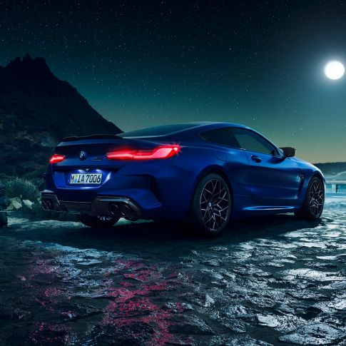 BMW M8|Coupe Competition, вид сзади с поворотом в три четверти F92. BMW M8 Coupe Competitionс включенными светодиодными задними фонарями, Синий Марина Бэй металлик, вид сзади с поворотом в три четверти, неподвижный автомобиль под полной луной F92.