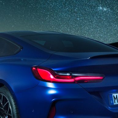 Задний спойлер M BMW M8 Coupe Competition, Синий Марина Бэй металлик, крупный план плечевой линии с задним спойлером M цвета Черный Карбон в темное время суток.