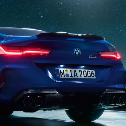 Диффузор M цвета “Черный Карбон”. BMW M8Coupe Competition, Синий Марина Бэй металлик, крупный план диффузора M цвета Черный Карбон в темное время суток.