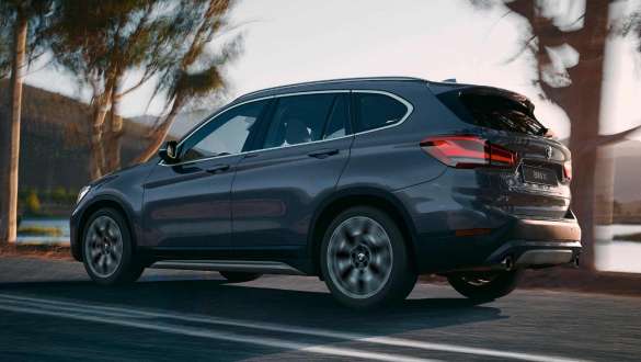 BMW X1, вид сзади с поворотом в три четверти. BMW X1 в движении, вид сзади с поворотом в три четверти на фоне гор.