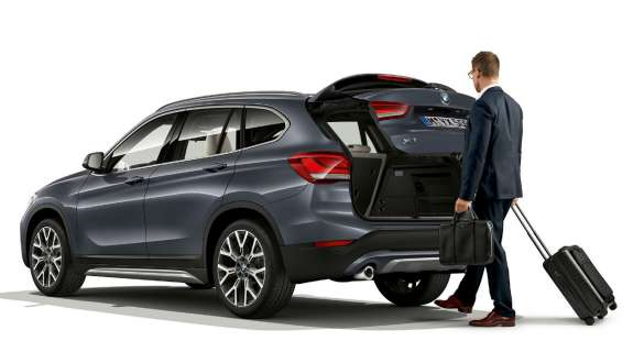 BMW X1, автоматическое управление задней дверью. BMW X1, вид стоящего автомобиля сбоку с открытой задней дверью.
