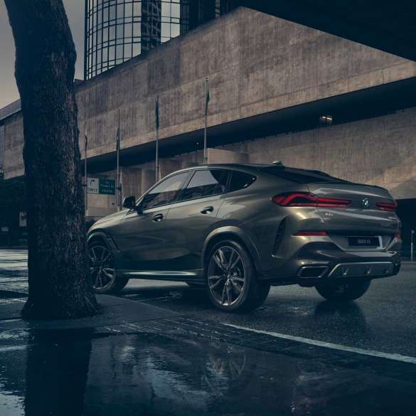 Экстерьер BMW X6 BMW X6, вид сзади с поворотом в три четверти на фоне города