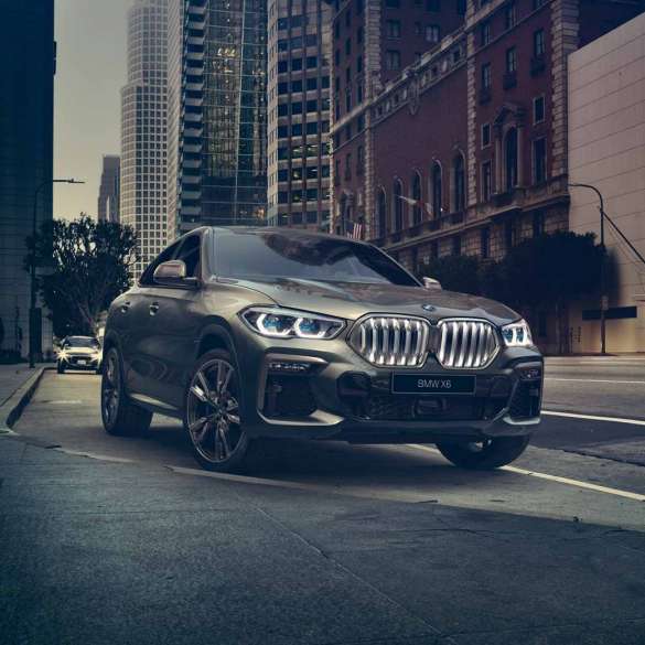 BMW X6 с адаптивной подвеской M с пакетом Professional BMW X6, вид спереди с поворотом в три четверти на фоне города