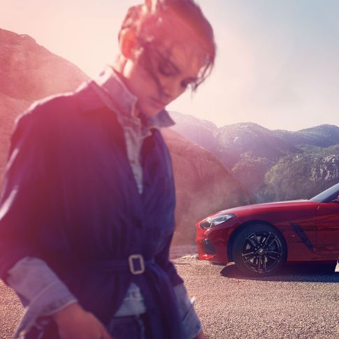 BMW Z4 Roadster на фоне горного пейзажа Мужчина и женщина рядом с BMW Z4 Roadster на фоне горного пейзажа