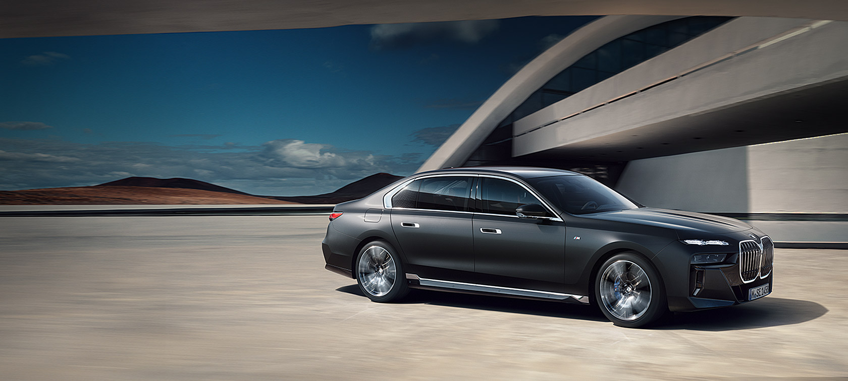 BMW 7 серии G70 ICE, пакет M Sport, "Морозный Насыщенный Серый металлик", вид спереди в три четверти, в статике перед зданием