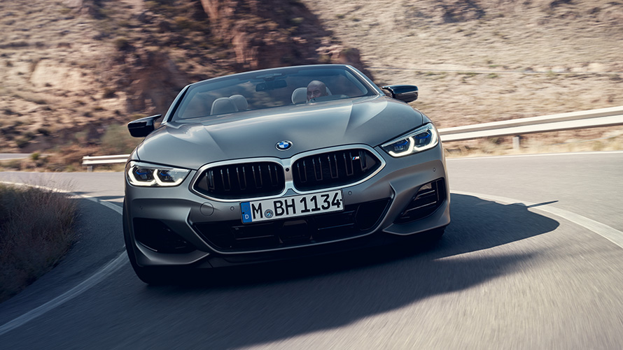 BMW 8 серии Cabrio, пакет M Sport G14 LCI Facelift 2022, вид спереди в движении на повороте BMW 8 серии Cabrio, пакет M Sport G14 LCI Facelift 2022 BMW Individual Морозный Чистый Серый металлик, вид спереди в движении на повороте