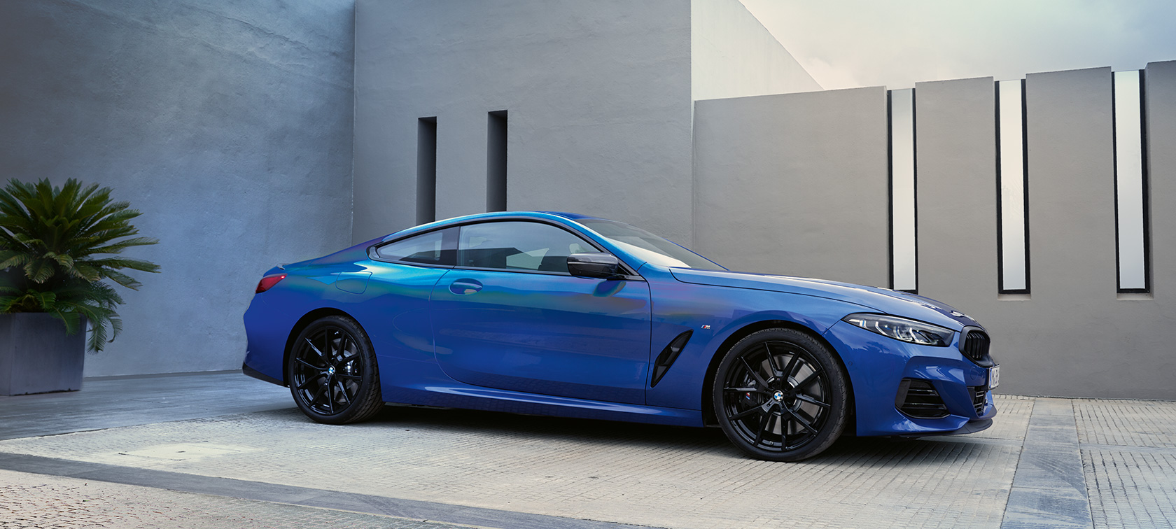 BMW 8 серии Coupe G15 LCI Facelift 2022, M Синий Портимау металлик, вид сбоку перед стеной здания