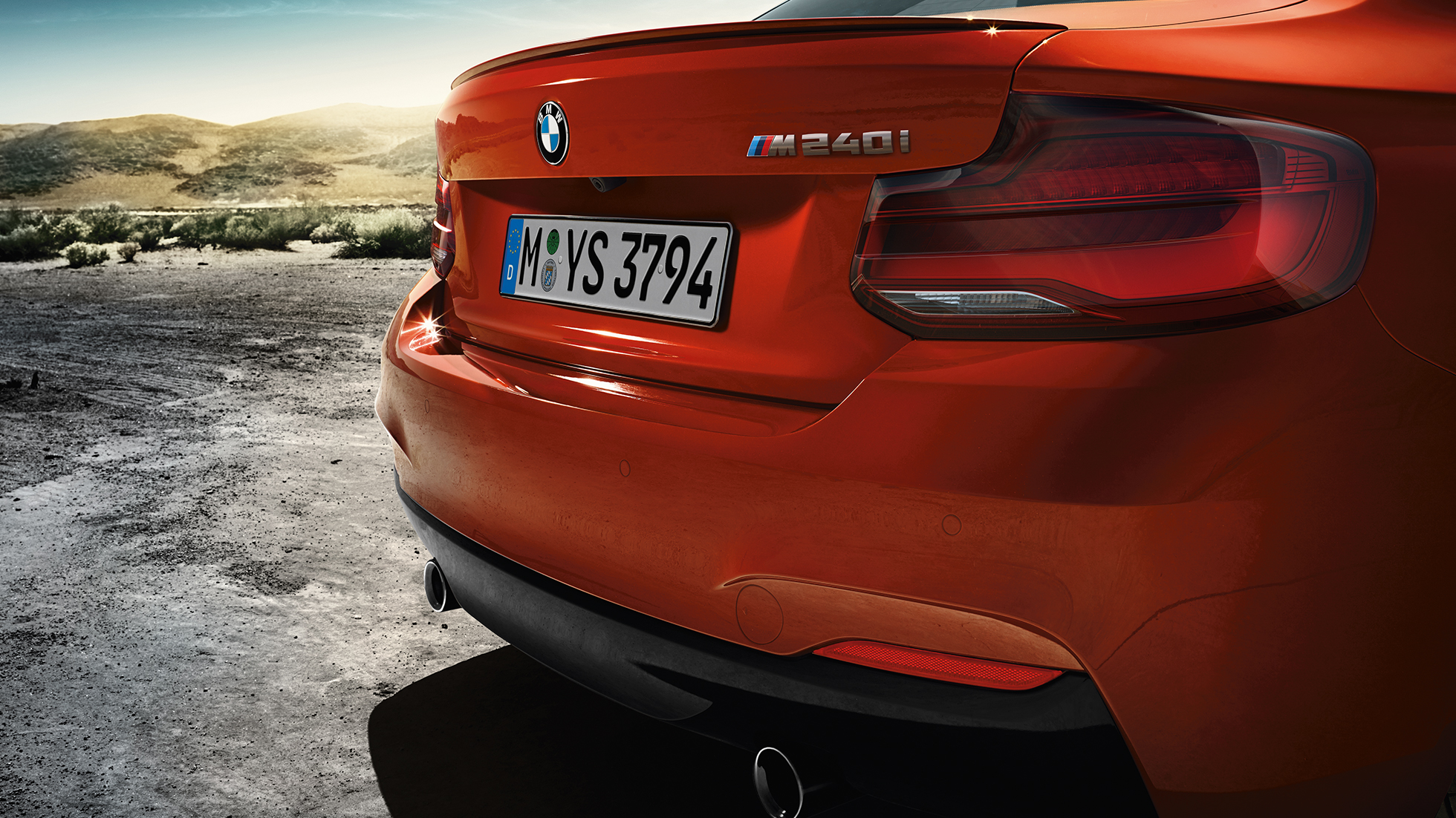 Дизайн задней части кузова BMW M240i Coupe Дизайн задней части кузова BMW M240i Coupe F22 2017 МГ цвета Оранжевый Закат (металлик), вид сзади с поворотом в три четверти