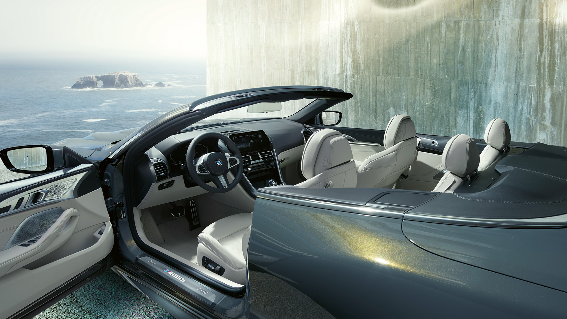 BMW M850i xDrive Cabrio, интерьер. BMW M850i xDrive Cabrioс открытым мягким верхом, Серый Дравит металлик, интерьер с акцентом на обтянутое кожей рулевое колесо M и отделку кожей Merino BMW Individual цвета «Слоновая Кость».