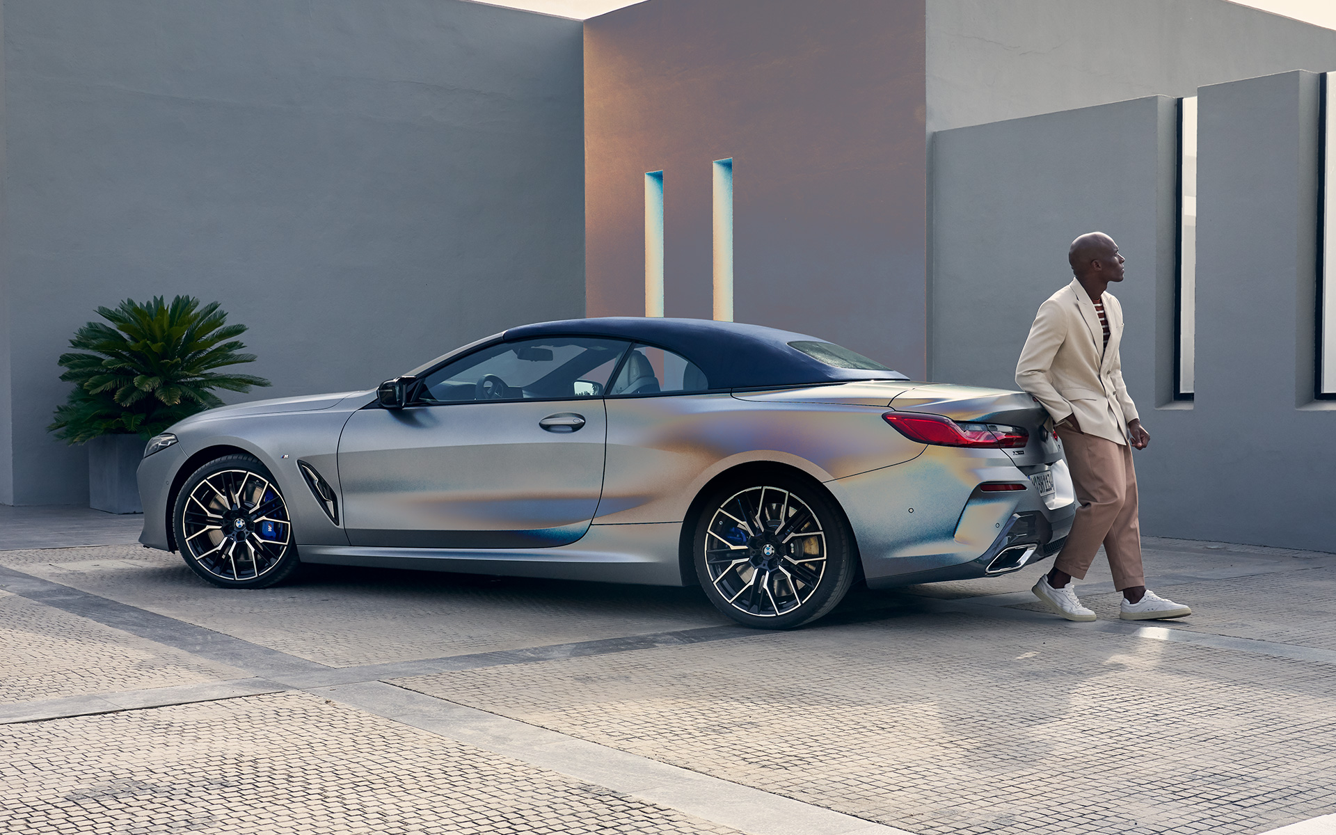 Вид сзади в три четверти BMW M850i xDrive Cabrio G14 LCI Facelift 2022 BMW M850i xDrive Cabrio G14 LCI Facelift 2022, BMW Individual Морозный Чистый Серый металлик, вид сзади в три четверти с мужчиной, опирающимся на автомобиль