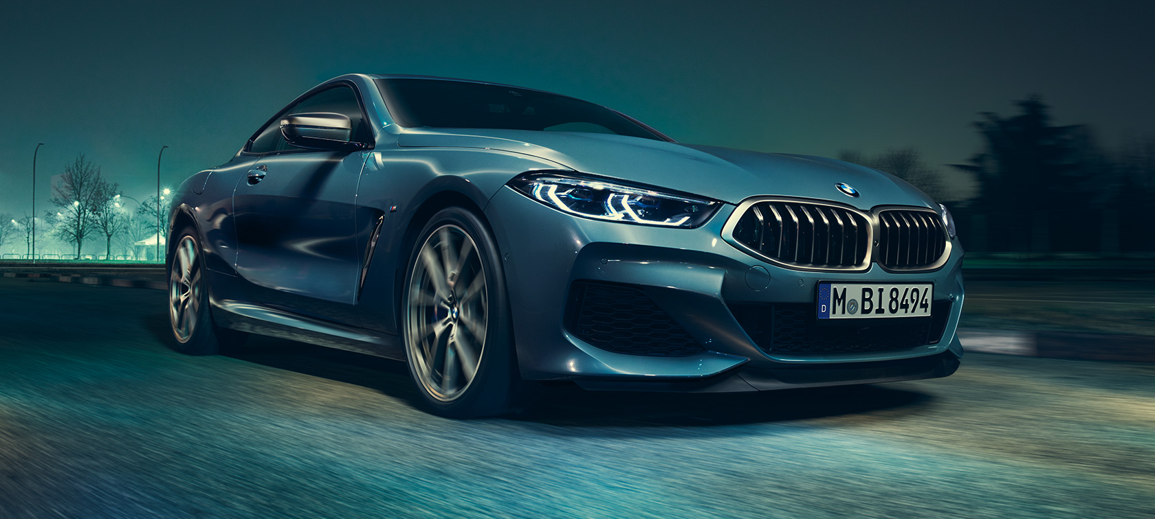 BMW M850i xDrive Coupe, вид спереди с поворотом в три четверти. BMW M850i xDrive Купе, Синий Барселона металлик, вид спереди с поворотом в три четверти, автомобиль в движении.