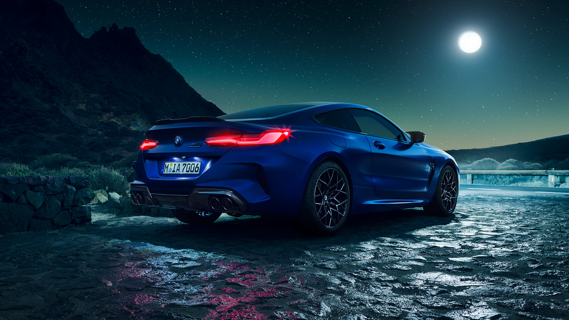 BMW M8|Coupe Competition, вид сзади с поворотом в три четверти. BMW M8 Coupe Competitionс включенными светодиодными задними фонарями, Синий Марина Бэй металлик, вид сзади с поворотом в три четверти, неподвижный автомобиль под полной луной.
