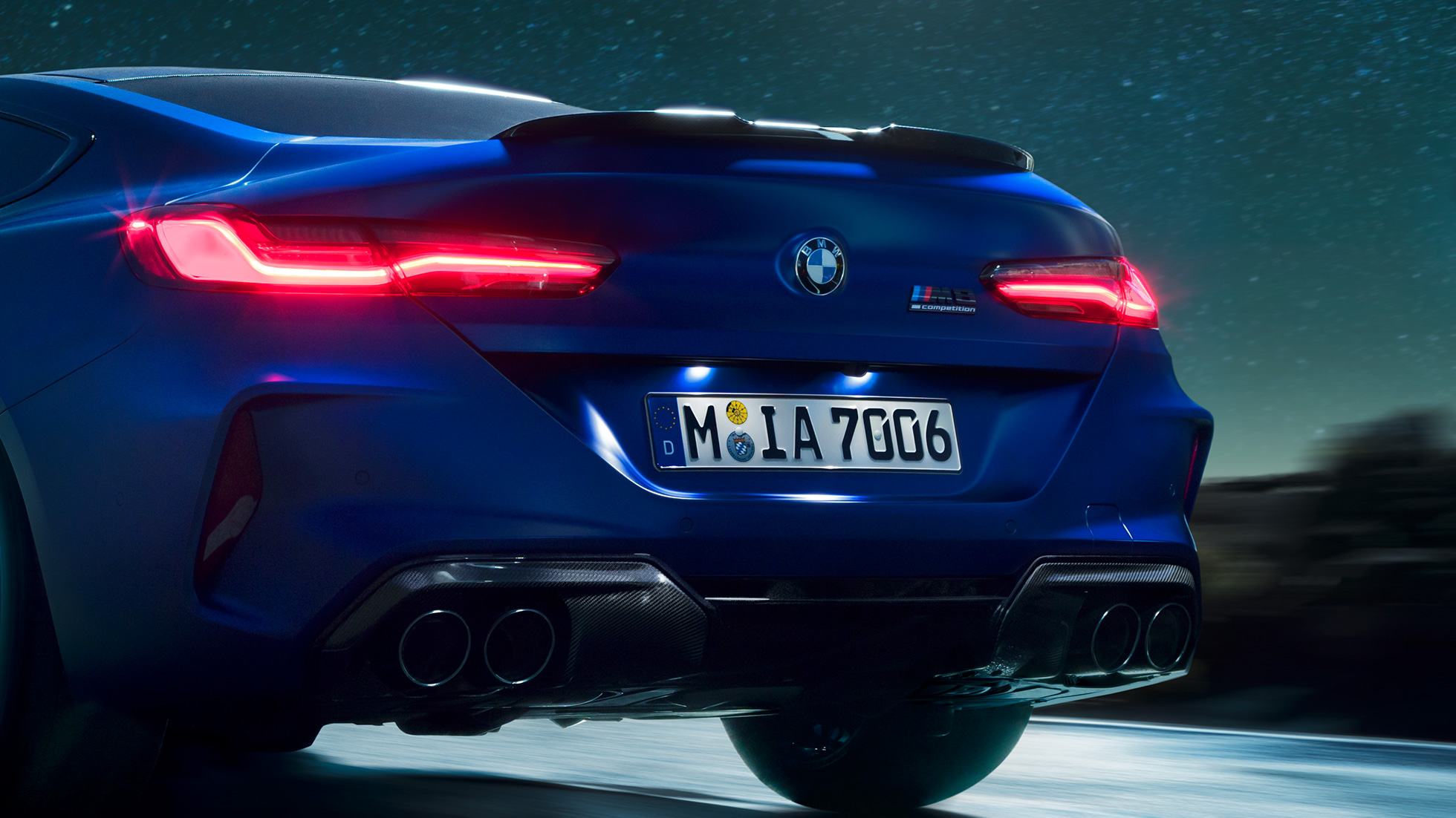 Диффузор M цвета “Черный Карбон”. BMW M8Coupe Competition, Синий Марина Бэй металлик, крупный план диффузора M цвета Черный Карбон в темное время суток.