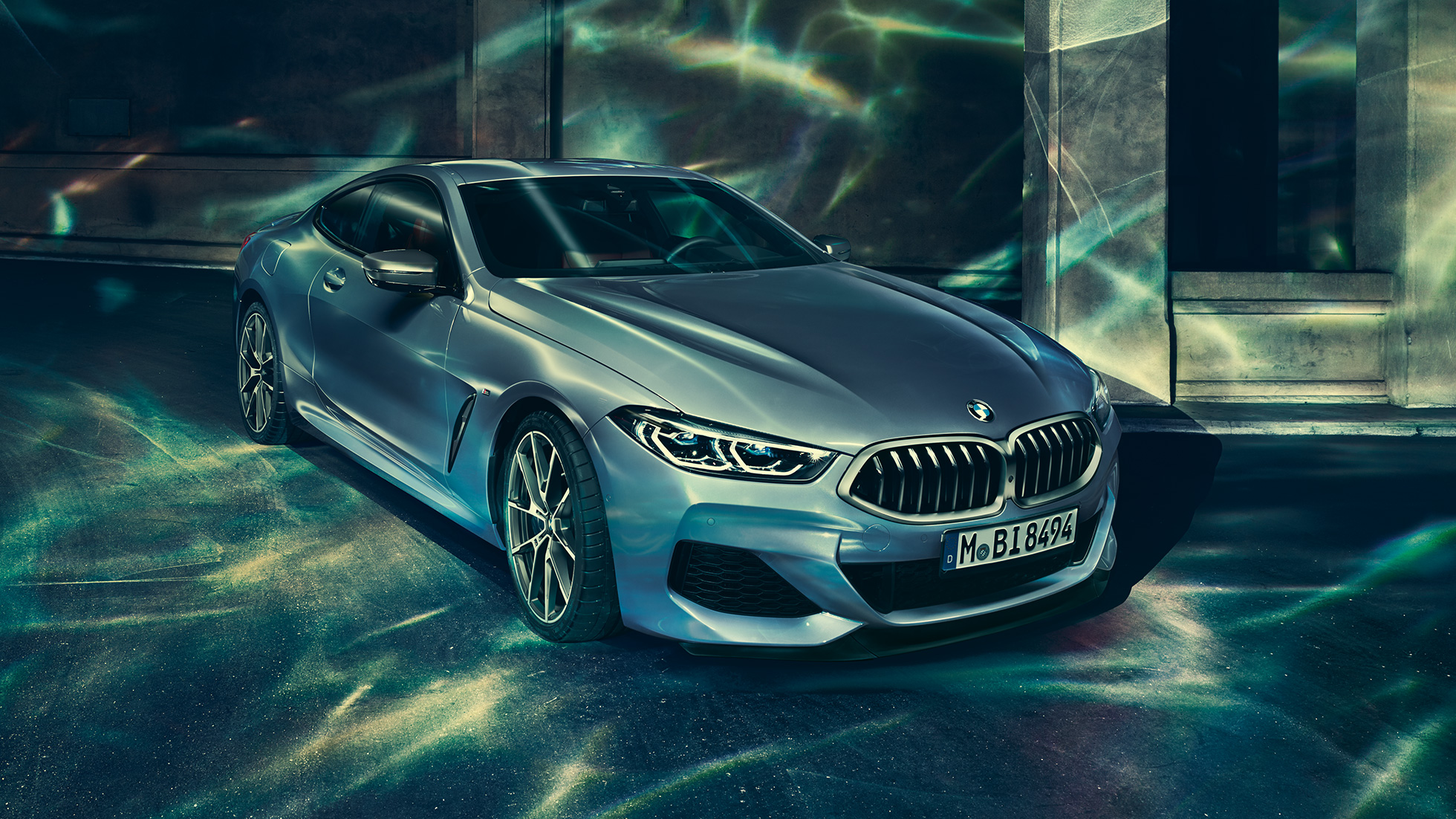 BMW M850i xDriveCoupe, вид спереди слева с поворотом в три четверти. BMW M850i xDriveCoupe, Синий Барселона металлик, вид спереди слева с поворотом в три четверти, неподвижный автомобиль перед зданием.