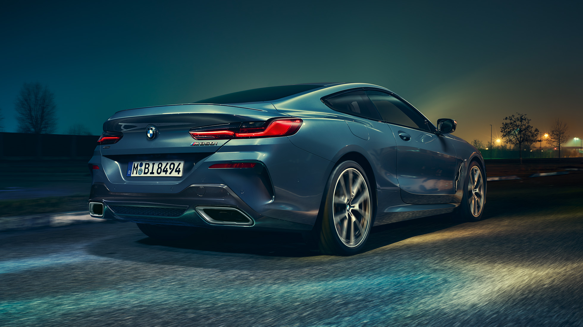 BMW M850i xDrive Coupe, вид сзади. BMW M850i xDrive Coupe, Синий Барселона металлик, вид сзади, автомобиль в движении в темное время суток.