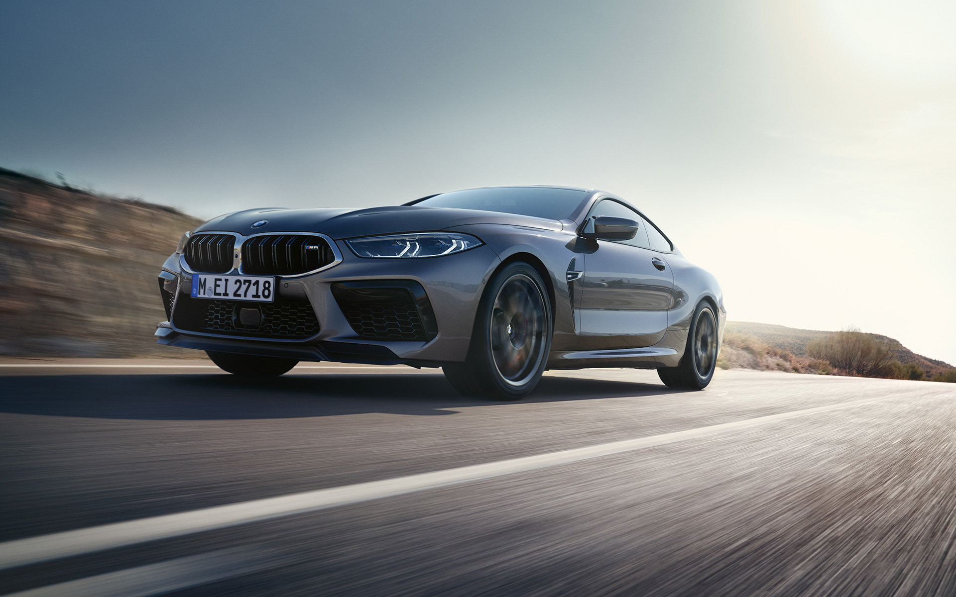 Вид спереди в три четверти BMW M8 Coupe F92 LCI Facelift 2022 в движении на магистрали BMW M8 Coupe F92 LCI Facelift 2022, "Серый Графит металлик", вид спереди снизу в три четверти в движении на магистрали
