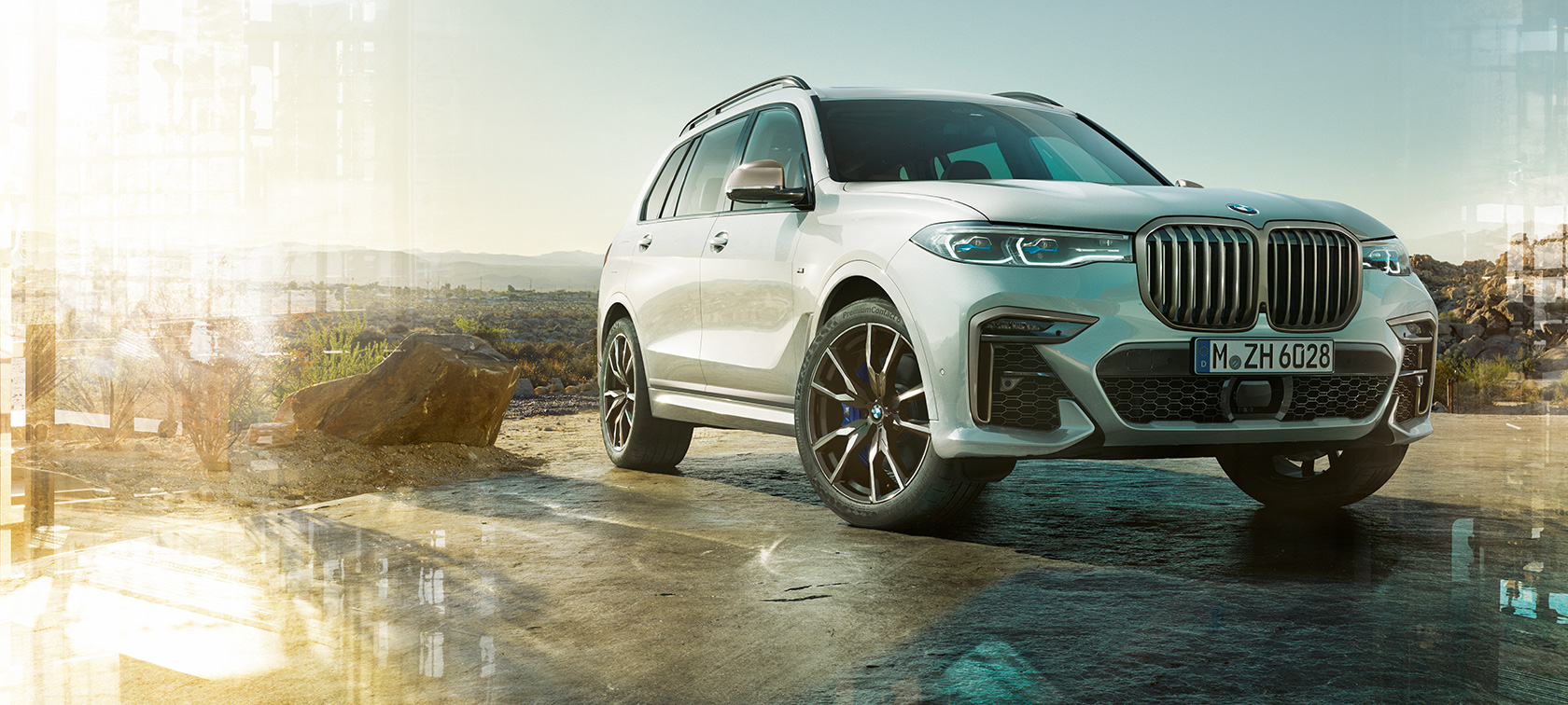 Автомобиль BMW X7 M SUV G07, вид спереди слева с поворотом в три четверти Автомобиль BMW X7 M SUV с кузовом белого цвета Mineral, G07, на стоянке, вид спереди слева с поворотом в три четверти