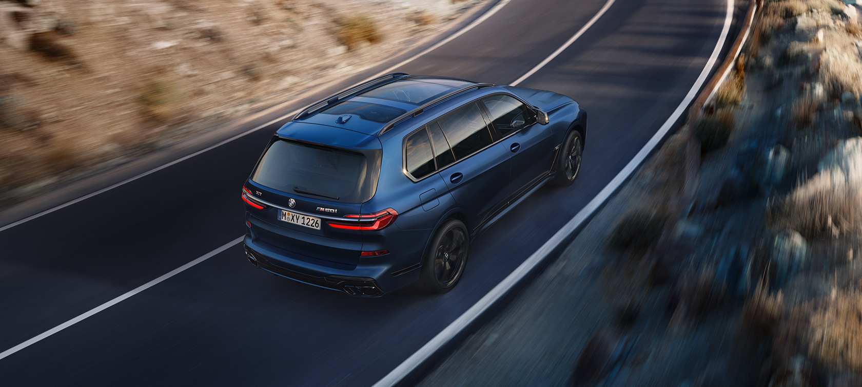 BMW X7 M60i xDrive G07 LCI, Морозный Синий Марина Бэй металлик, вид сзади в три четверти с высоты птичьего полета на улице в движении 