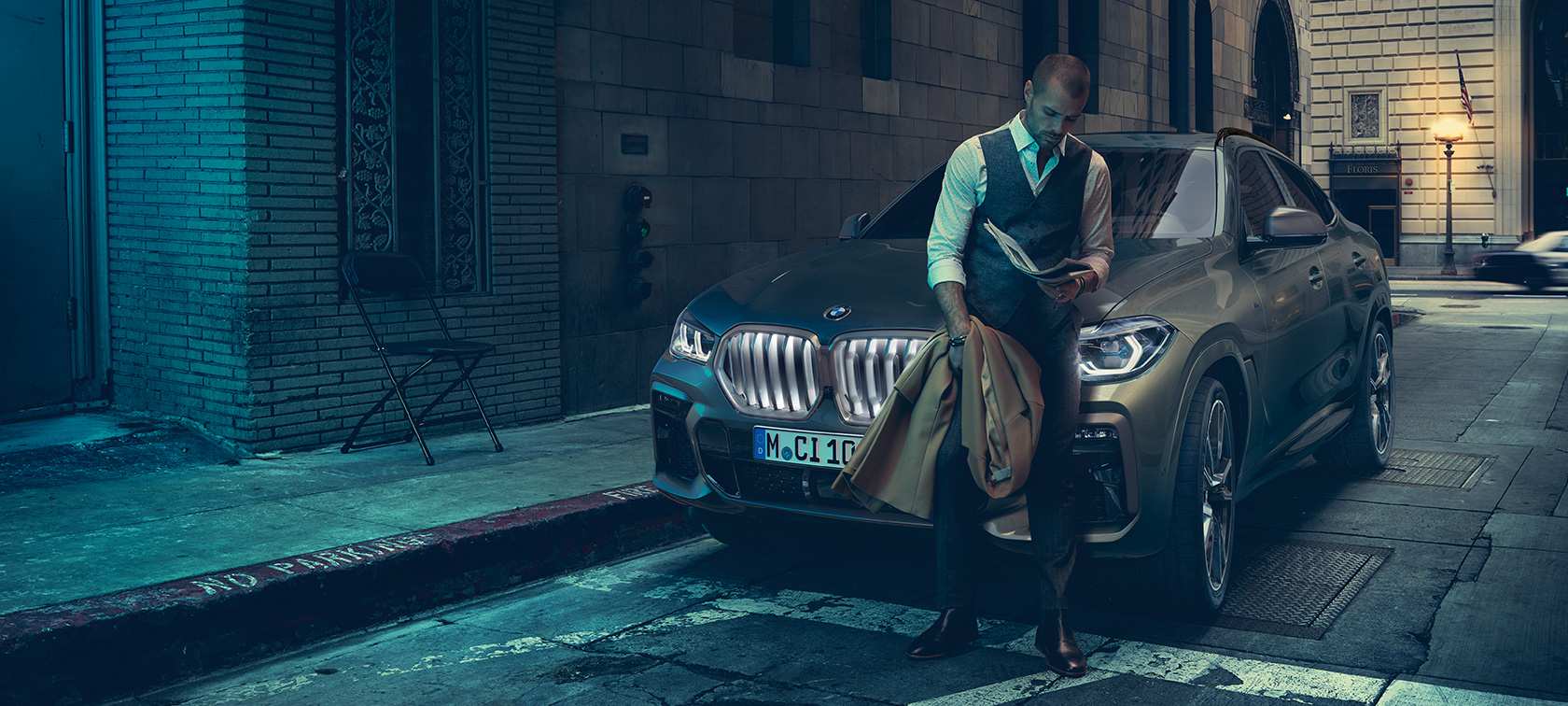 Мужчина опирается на BMW X6 Мужчина опирается на BMW X6, вид сбоку на фоне города