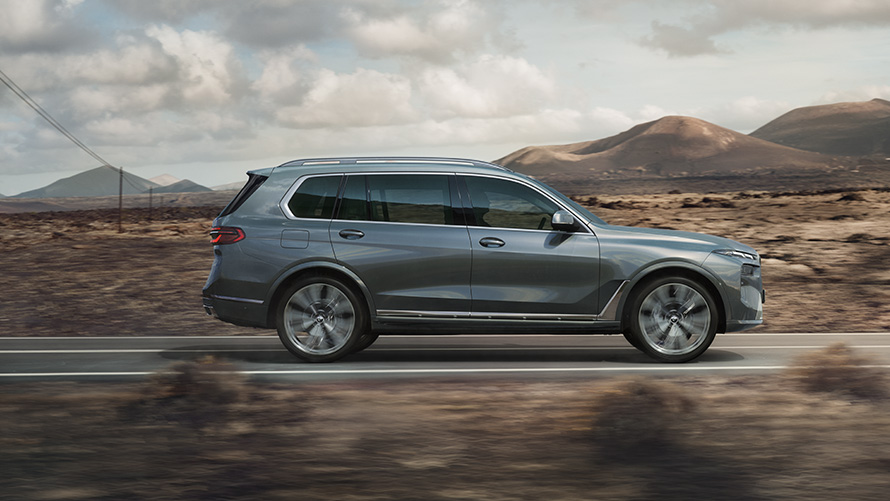 BMW X7 G07 LCI, вид сбоку, Искрящийся Медный Серый металлик BMW X7 G07 LCI, вид сбоку в движении, Искрящийся Медный Серый металлик