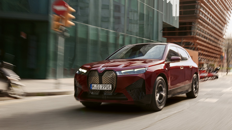 BMW iX3 G08 2021, вид спереди в три четверти, в движении, перед туманным холмистым пейзажем