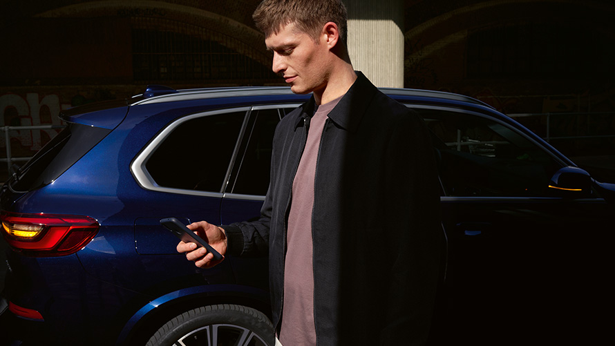 Цифровой ключ Digital Key – для пяти пользователей Цифровой ключ BMW Digital Key максимум для пяти пользователей, мужчина со смартфоном перед BMW X5