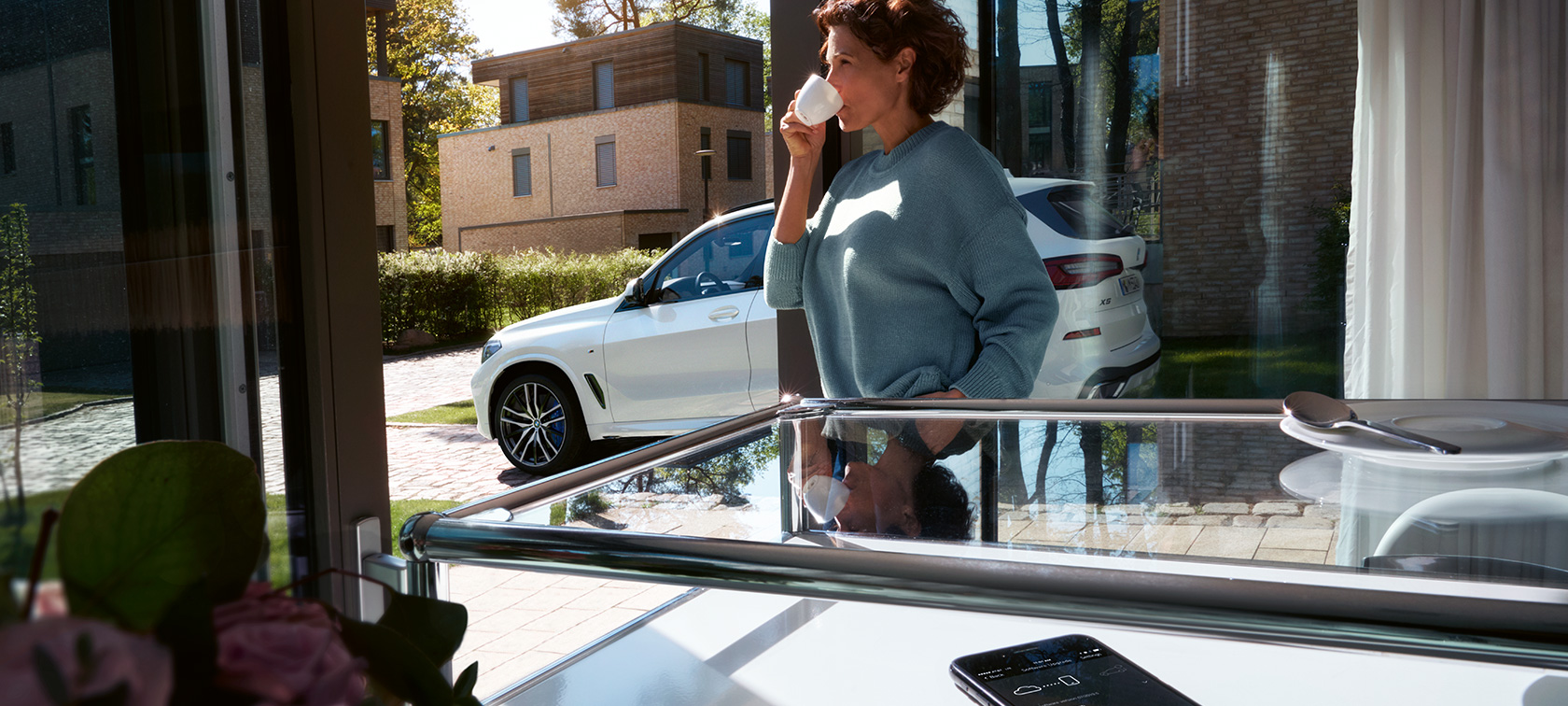 BMW Remote Software Upgrade Женщина пьет из чашки, ожидая обновления программного обеспечения ее BMW X5 при помощи BMW Remote Software Upgrade