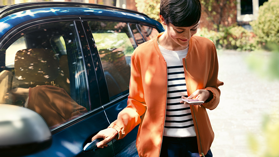 BMW Teleservices BMW Teleservices, женщина со смартфоном перед своим BMW
