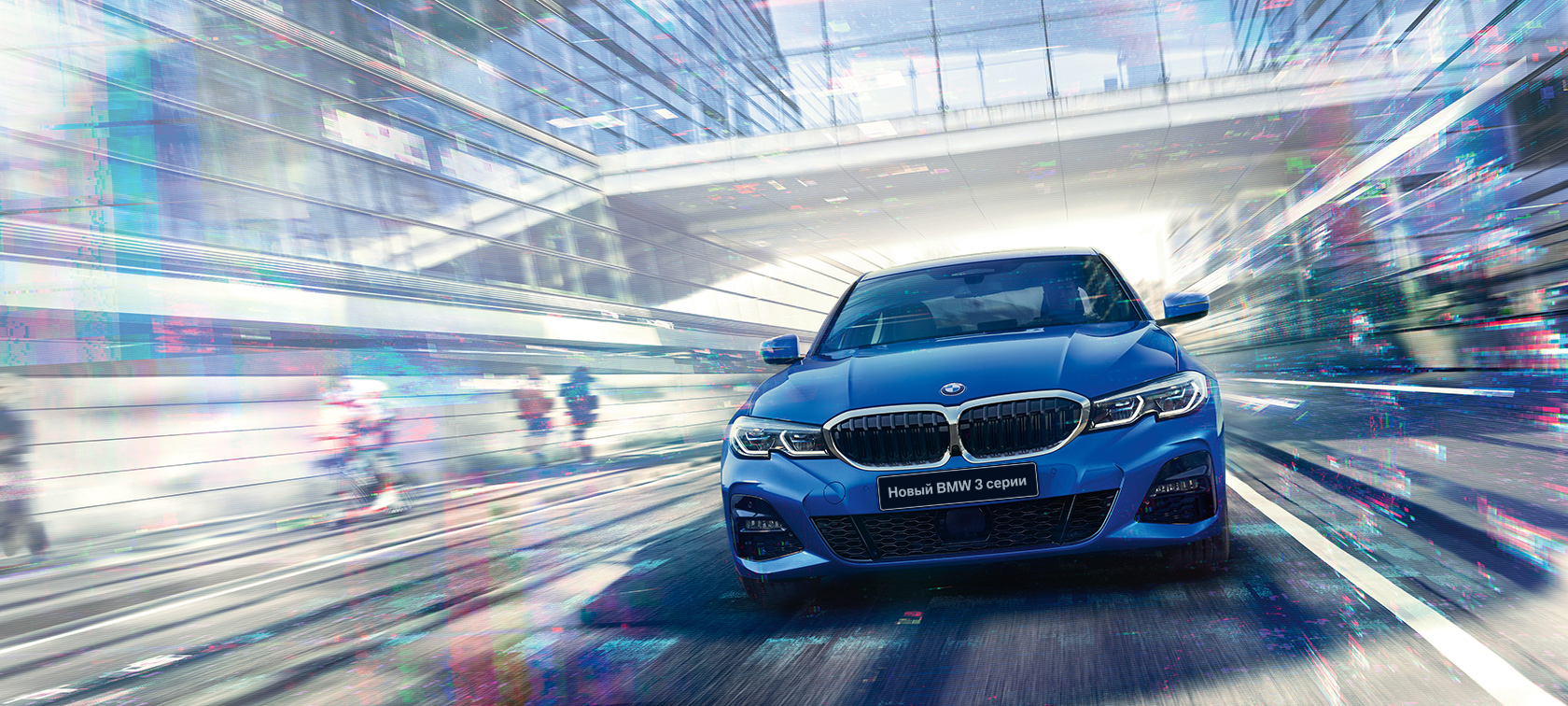 Седан BMW 3 серии, вид спереди Вид спереди седана BMW 3 серии в движении в дневное время на фоне здания со стеклянным фасадом.
