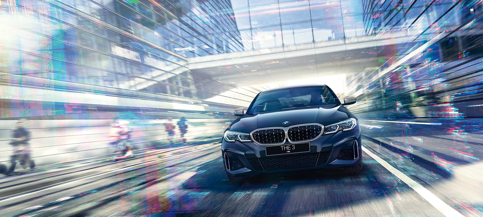 Седан BMW 3 серии, вид спереди Вид спереди седана BMW 3 серии в движении в дневное время на фоне здания со стеклянным фасадом.