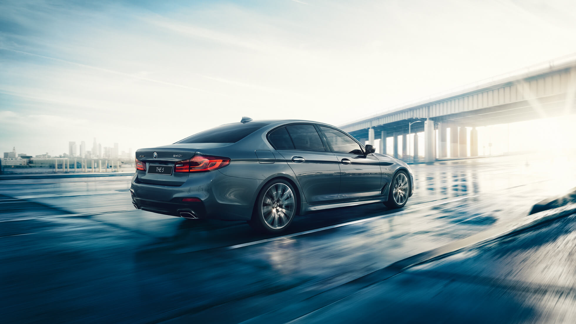 BMW 5 серия Седан, вид сзади с поворотом в три четверти. BMW 5 серия Седан, вид сзади с поворотом в три четверти, БМВ 5 седан, на рассвете, за городом, на шоссе.