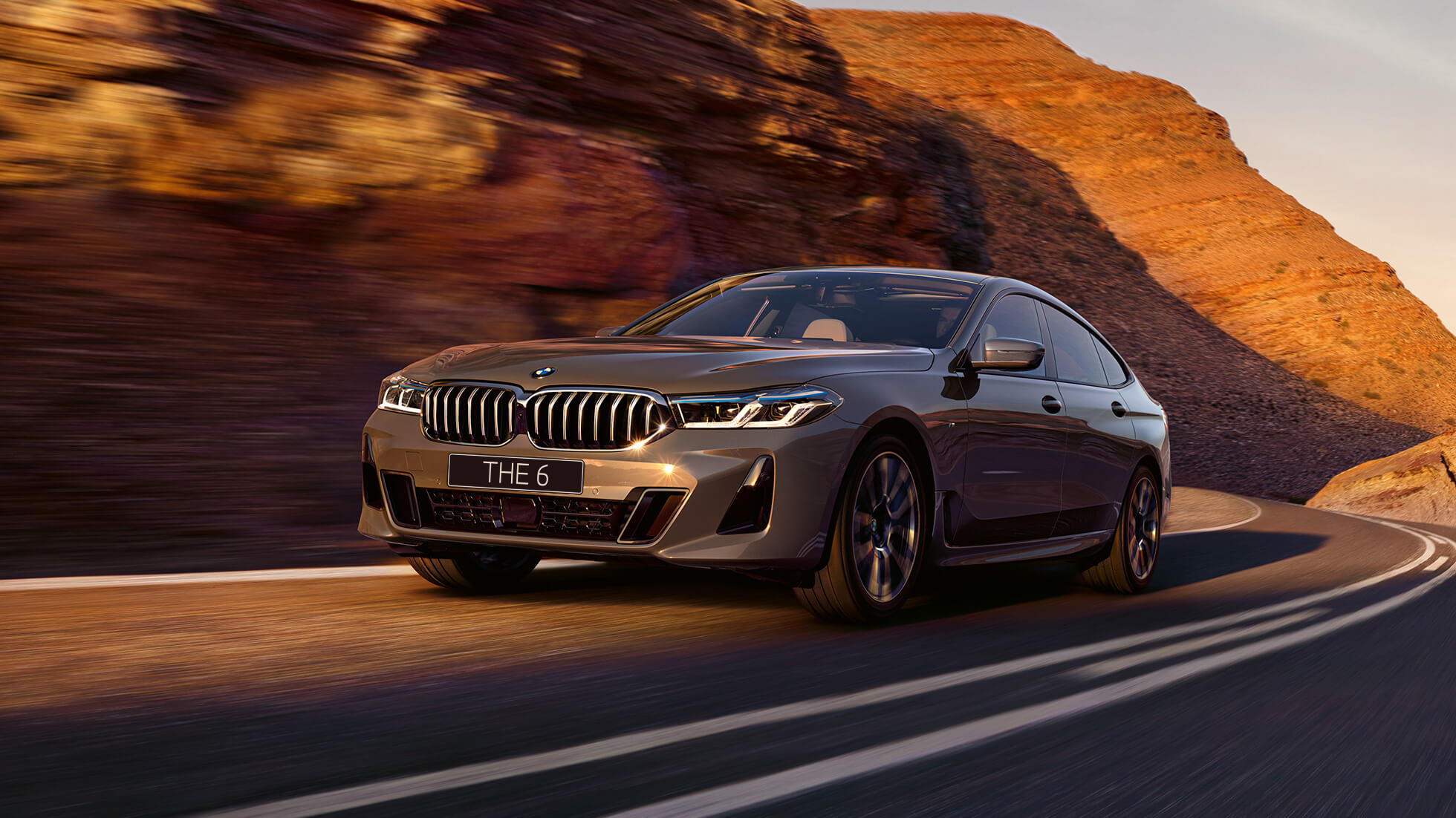 BMW 6 серии GT G32 2020 года BMW 6 серии GT 640i xDrive G32 2020 года, цвет «Серый Бернина», в движении на фоне природы, вид спереди с поворотом в три четверти