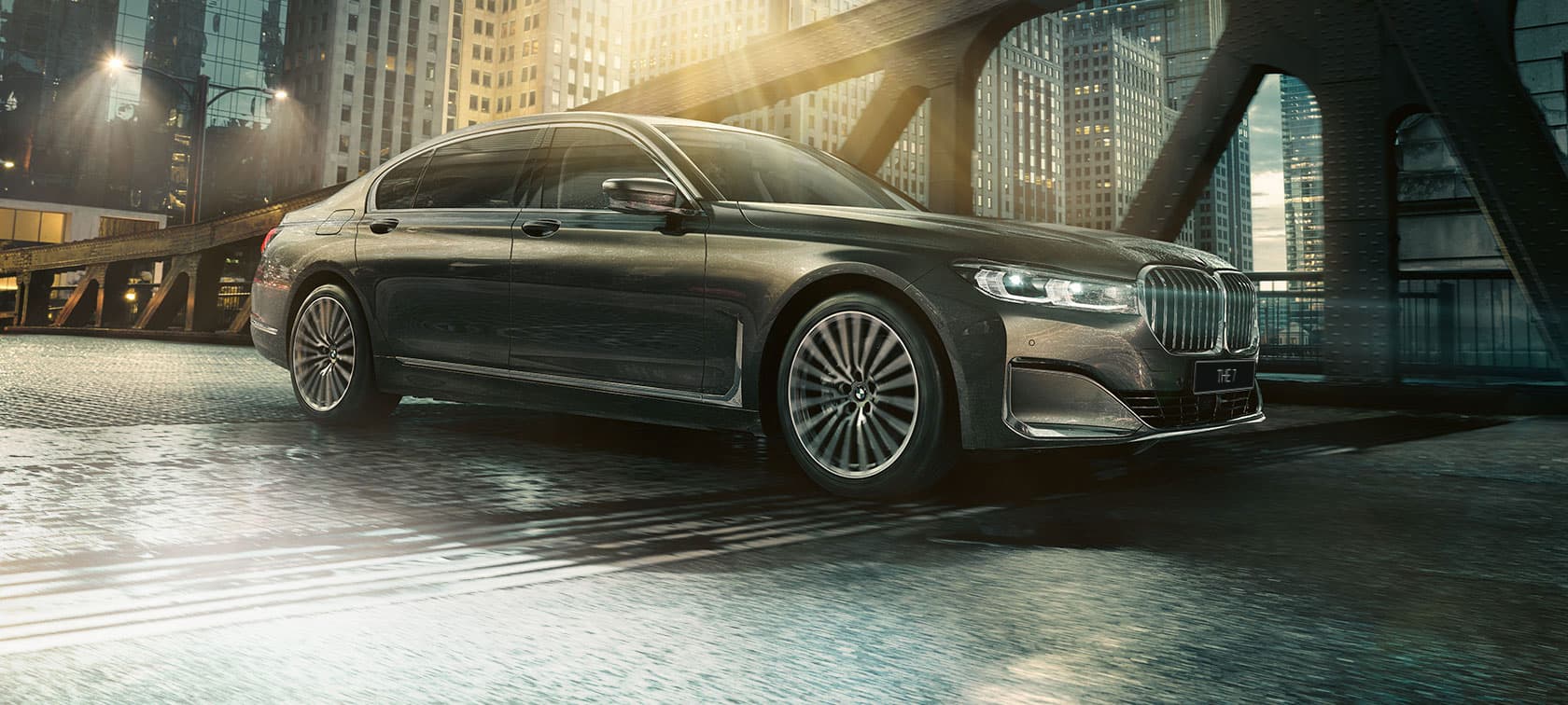 BMW 7 серии: вид сбоку G11 BMW 7 серии: вид сбоку с открытой дверью на фоне освещенного здания гостиницы G11