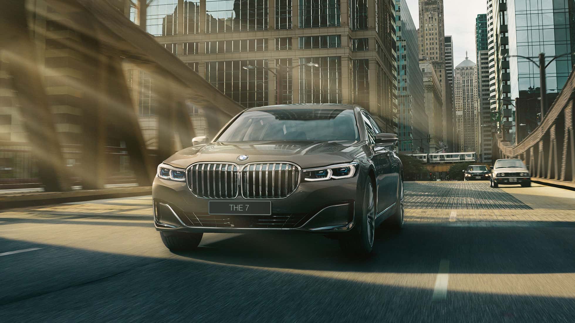 BMW 7 серии: системы помощи водителю G11 Системы помощи водителю: седан BMW 7 серии в движении на фоне городского пейзажа G11