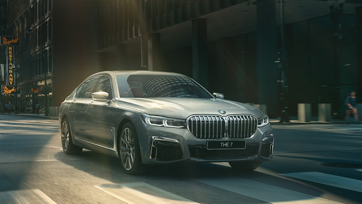 Пакет систем помощи водителю Driving Assistant Professional седана BMW 7 серии G11 Ассистент вождения Professional: BMW 7 серии в движении на фоне городского пейзажа, вид спереди с поворотом в три четверти G11