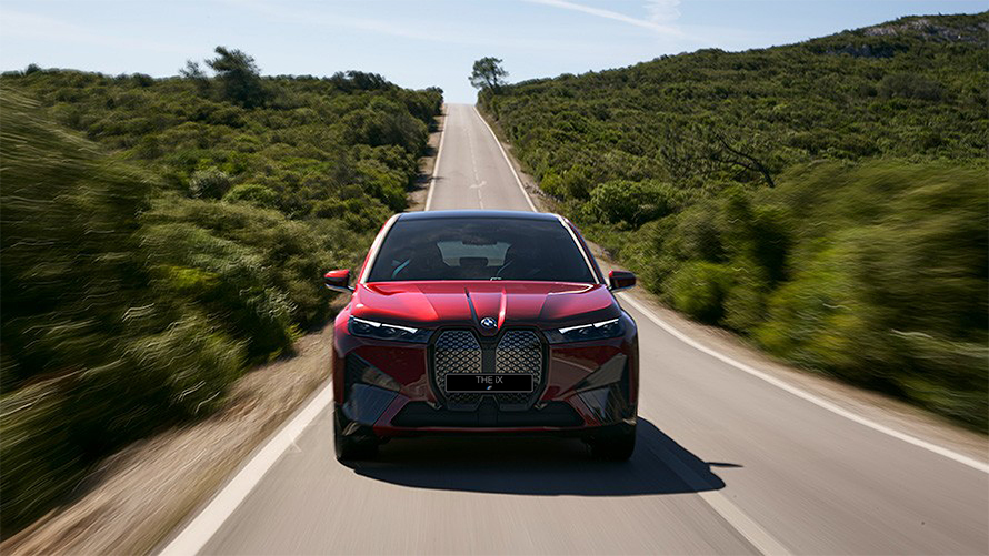 Электрический SUV BMW iX i20 2021, BMW iX xDrive50 "Красный Авантюрин" в движении на улице, запас хода