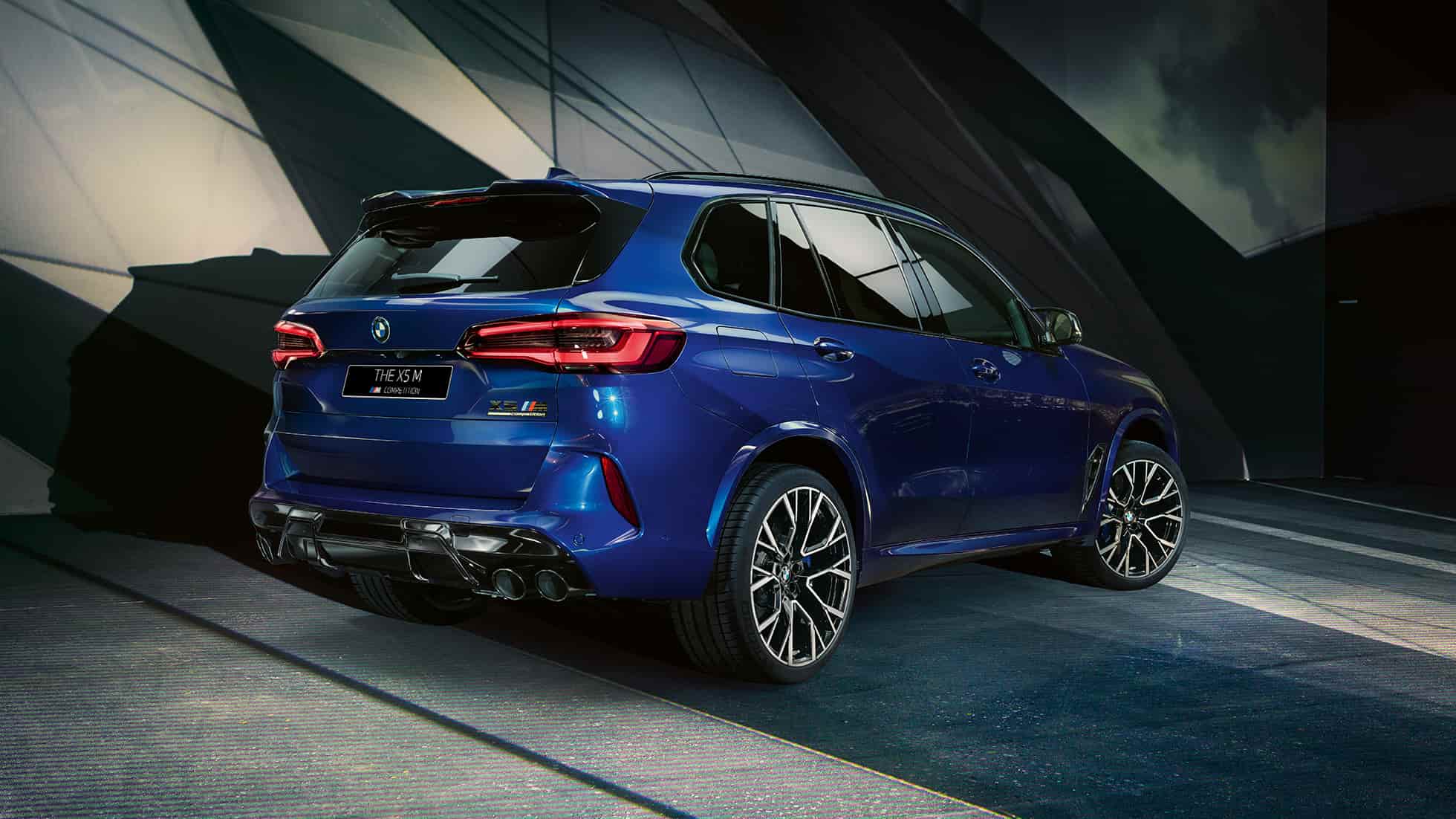 BMW X5 M Competition SUV F95, вид сзади с поворотом в три четверти BMW X5 M Competition SUV F95 со спортивной системой выпуска M в синем цвете Marina Bay (металлик), вид сзади с поворотом в три четверти